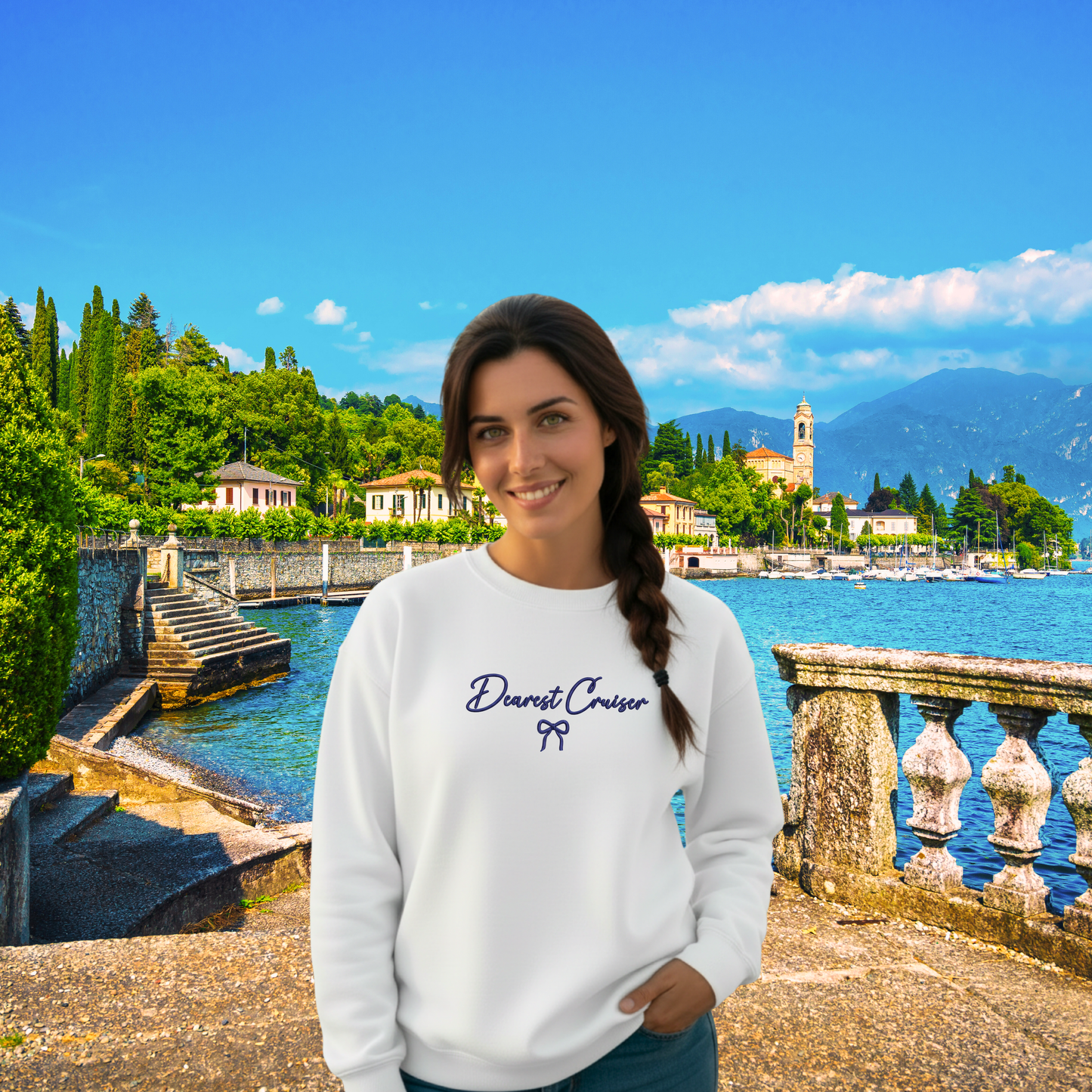 Woman wearing a white sweatshirt with text in front of a scenic lake and mountains.