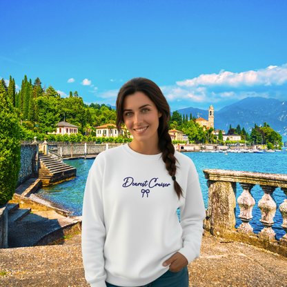 Woman wearing a white sweatshirt with text in front of a scenic lake and mountains.